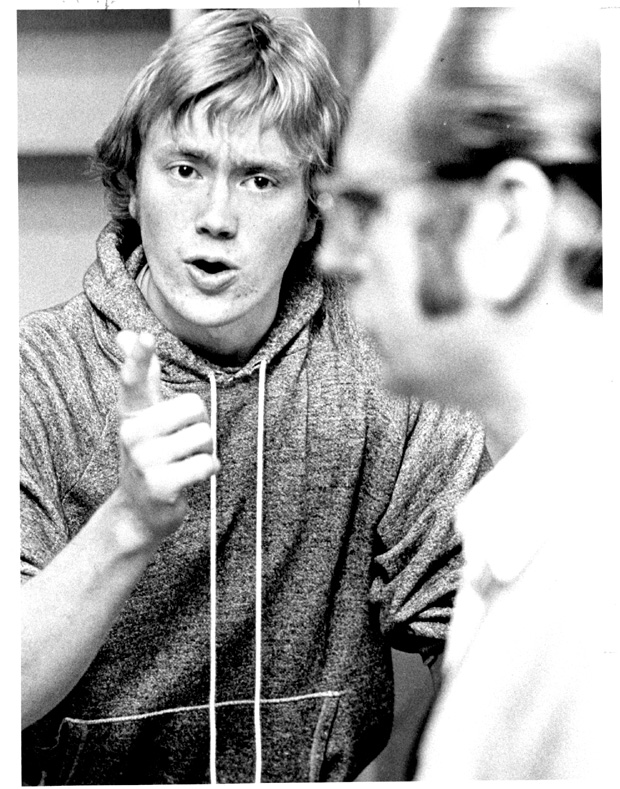 A black and white photograph from 1972 of John A. Peters wearing a hoodie in rehearsal, pointing his finger at Werner Regier playing the father, Alfred.